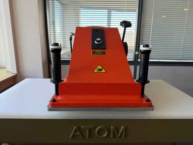 Presse à chaud rouge montée sur le plateau de la presse Atom, molette de réglage de température.